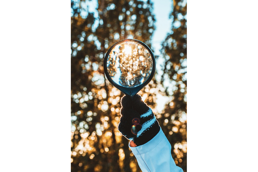 A person holding a magnifying glass up in the air
